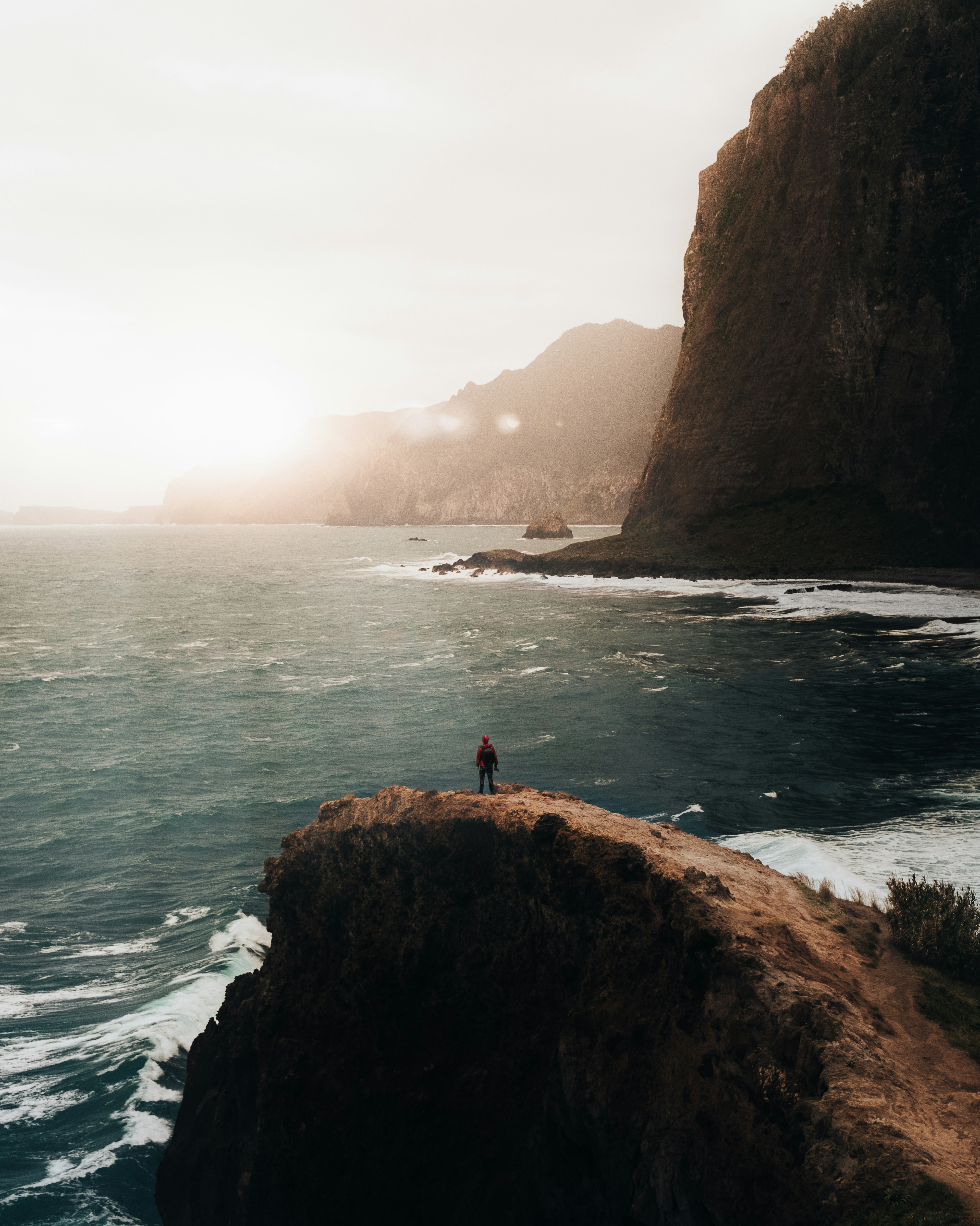 A person standing on a coastal overlook above the sea.